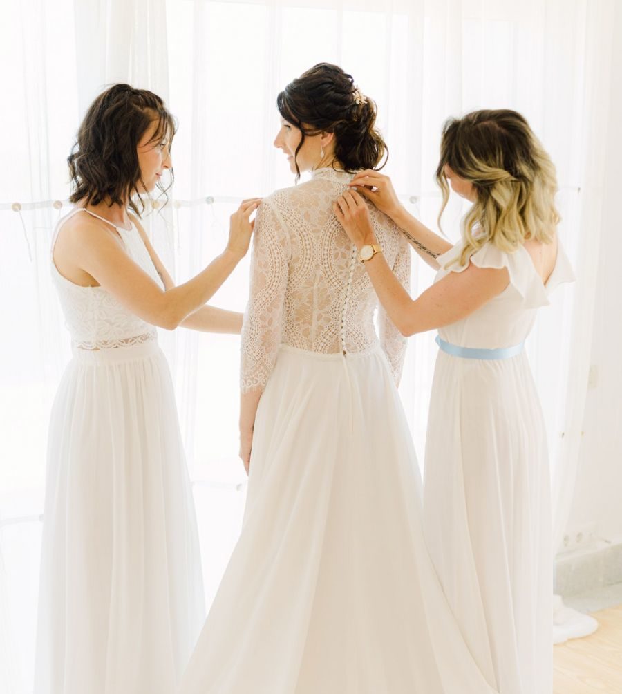 Bride being helped to get ready by her 2 bridesmaids